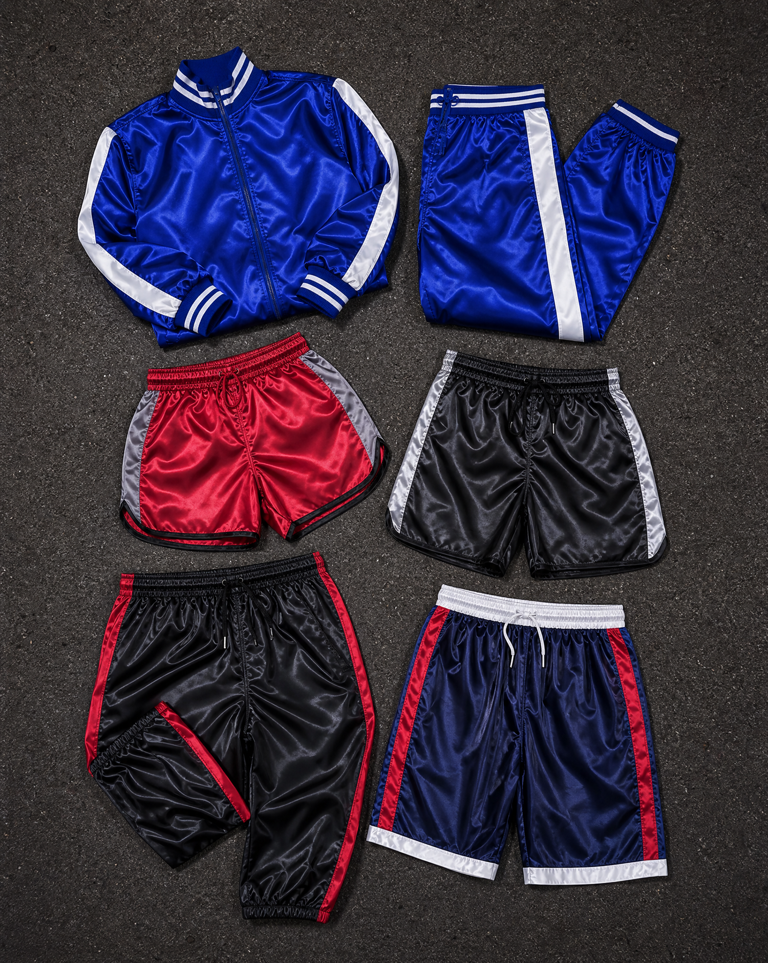 Satin tracksuit, track pants, retro shorts and boxing shorts laid out on asphalt — D-Mode Welt Satin Collection